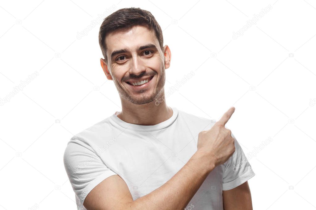 Attractive young man in white t-shirt pointing right with his finger isolated 