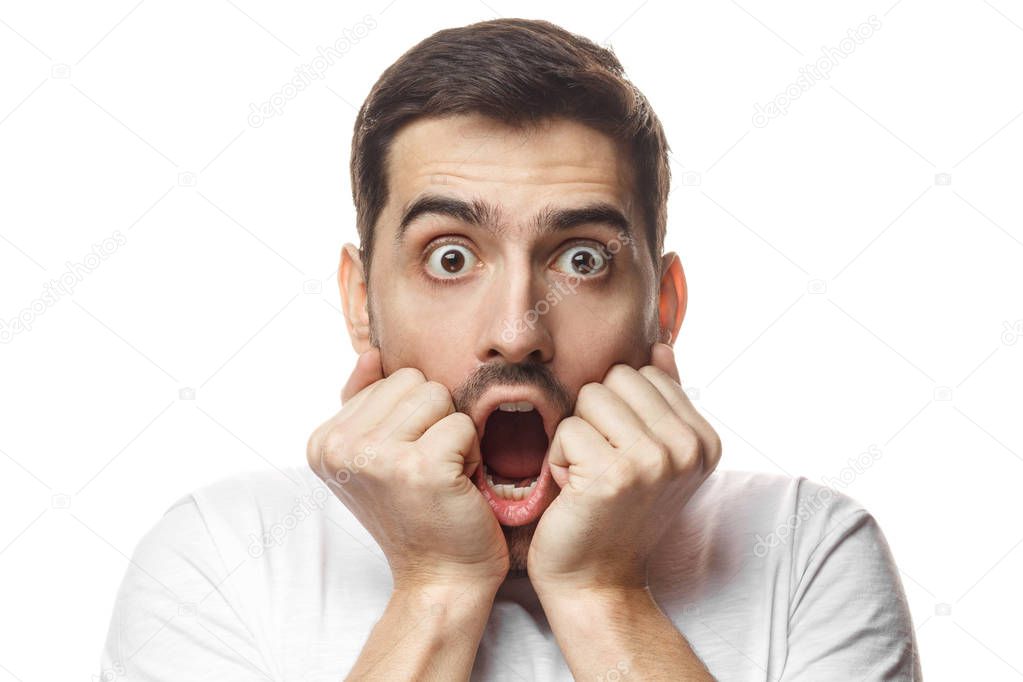 Surprised, embarrassed and confused young guy showing omg emotion. Astonished bug-eyed man covering his mouth with both hands, looking shocked