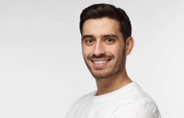 Yatay headshot, genç yakışıklı Avrupa beyaz adam mutlu bir şekilde gülümseyerek casual beyaz T-shirt ve kamera seyir vasıl dostu emin ve rahat giyen resimde izole üzerinde gri arka plan