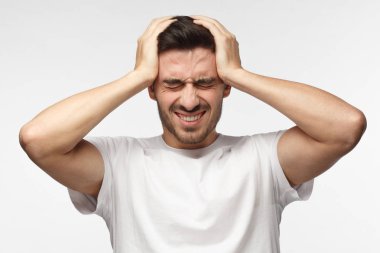 Avrupa beyaz adam izole üzerinde gri arka plan beyaz T-shirt sıkıca basarak kötü baş ağrısı, yaşayan tapınaklar gözleri yüzünden acıyı eller giymiş genç closeup headshot