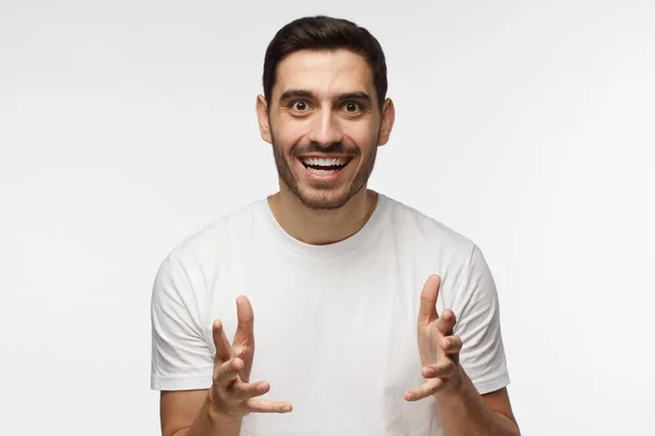 Photo rapprochée d'un bel homme caucasien photographié isolé sur fond gris vêtu d'un T-shirt décontracté tirant les mains vers l'avant et souriant comme s'il attendait une balle dans le jeu ou le profit qu'il veut obtenir — Photo