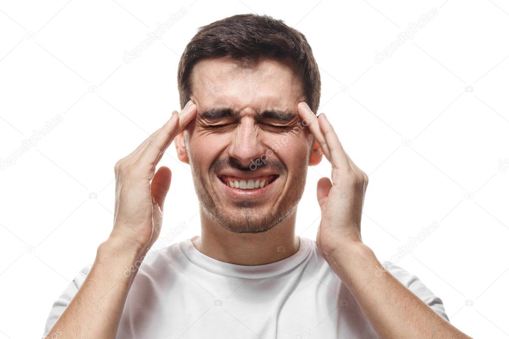 Headshot picture of European male isolated on white background wearing casual T-shirt having eyes closed, pressing fingers to temples in gesture of intensive concentration, trying to find answer
