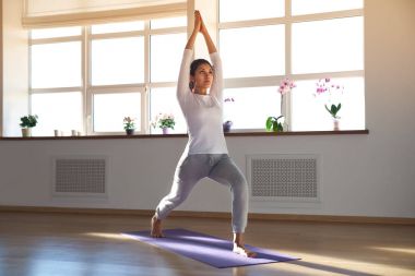 genç çekici sportif kadın parlak güneşli bir odada yoga yaparken,