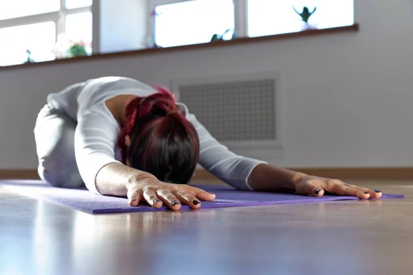 young woman does yoga exercises on a Mat lying face down with ou