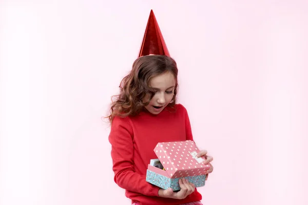 Bonita joven con una gorra de cumpleaños en la cabeza con una sorprendida —  Fotos de Stock