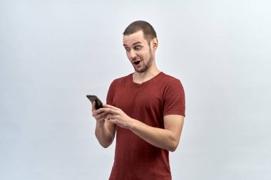 sürpriz telefon çılgın şok bak ve açık ağızlı iki eliyle tutarak genç bir beyaz erkek portresi.