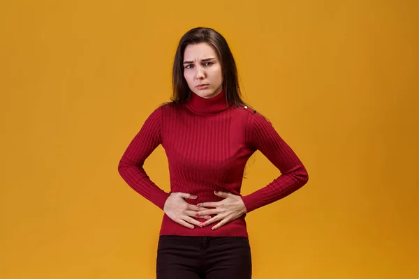 Uma jovem atraente agarrou seu estômago de dor de abdômen inferior, ciclo menstrual não dá descanso para fazer o trabalho — Fotografia de Stock