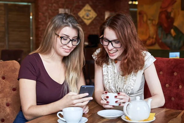 Porträtt av två unga vackra tjejer kvinnor kommunicera och splenocolic vid ett bord på ett café — Stockfoto