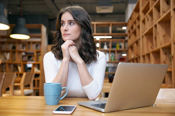 Giovane attraente ragazza donna elegante in abiti casual seduto a un tavolo in un caffè con un computer portatile — Foto Stock