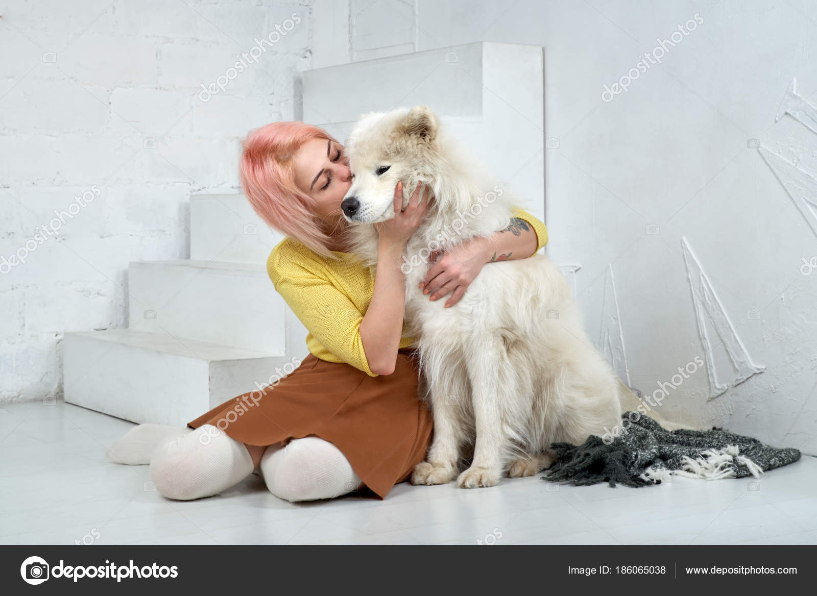 Young Girl Kissing And Hugging A Large White Friend Dog Samoyed