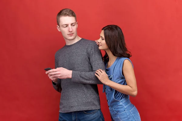 Güzel esmer kadın bakışları inanmazlıkla erkek arkadaşı telefon için casusluk yanan