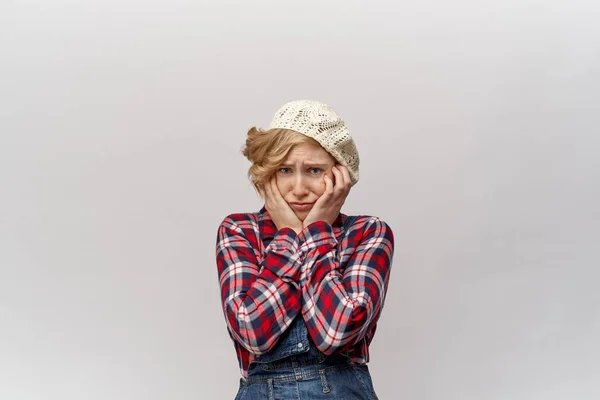 Atractiva joven estudiante rubia en ropa anticuada en estilo retro como un montañés en la confusión agarra su cara en las manos — Foto de Stock
