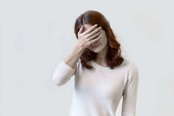 Retrato de mujer joven con el pelo largo en camisa blanca que cubre sus manos y la cara que muestra vergüenza y descontento, facepalm — Foto de Stock