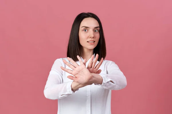 Una giovane bruna dalla pelle bianca con una camicia bianca tira le mani e incrocia le palme davanti a lei — Foto Stock