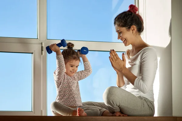 Egy fiatal anya örül a sikert, a lánya, sport gyakorlatok. Fiatal család, promóció, az egészséges életmód, sport — Stock Fotó