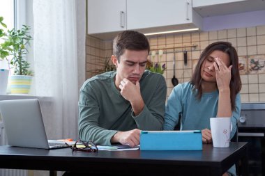 mutfak masasında oturan genç çift planlama ve mali hesaplama nişanlandık. Yorgun yüz ve olumsuz duygular