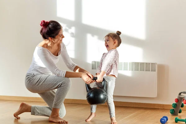 Anne ve kızı neşeli olumlu duygular ile spor için içeri girip ağırlıkları birlikte büyüteceğiz.