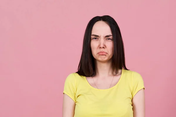 Sconvolto dalla caricatura di una triste ragazza bruna in camicia gialla, fa un viso e sporge il labbro inferiore. Grande Studio ritratto — Foto Stock