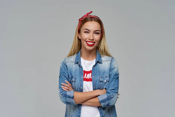 çekici genç kadın geniş gülümseyerek ellerini göğsüne katlanmış. Rahat kıyafet kot gömlek ve t-shirt.