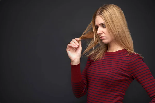 Chica joven se ve molesto en los rizos de su cabello y piensa en cómo darles aspecto saludable y deshacerse de las puntas abiertas — Foto de Stock