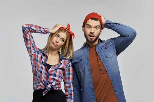 Divertida pareja joven de hipsters en ropa casual y con sombreros tomados de la mano detrás de sus cabezas — Foto de Stock