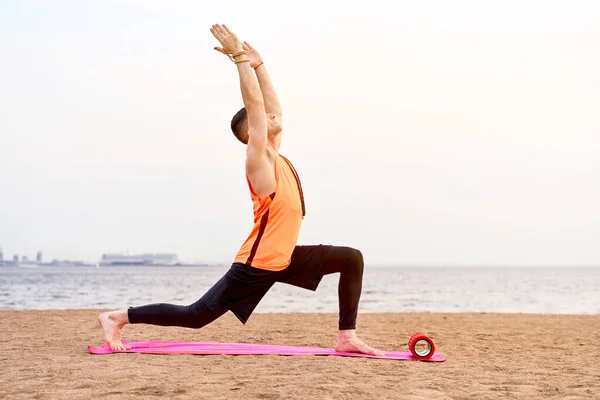 Atlético homem fazendo ioga asanas na natureza, areia do mar — Fotografia de Stock