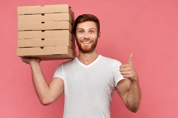 Courier holds many pizza boxes isolated on wall