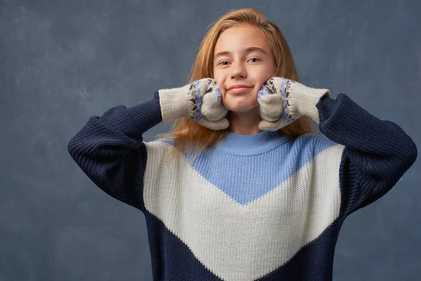 Teenage girl blonde in warm sweater isolated wall