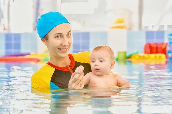 Young mother and baby son are in pool teaches swim