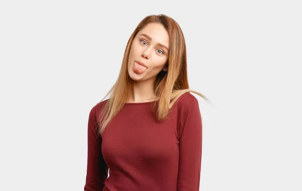 Menina engraçada faz rostos furando sua língua — Fotografia de Stock