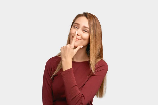 Rolig flicka håller pekfingret på näsan, ler — Stockfoto