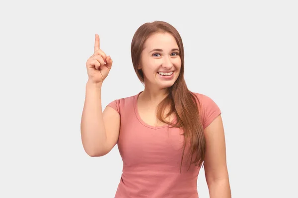 Flicka ler brett och pekar hennes pekfinger upp — Stockfoto