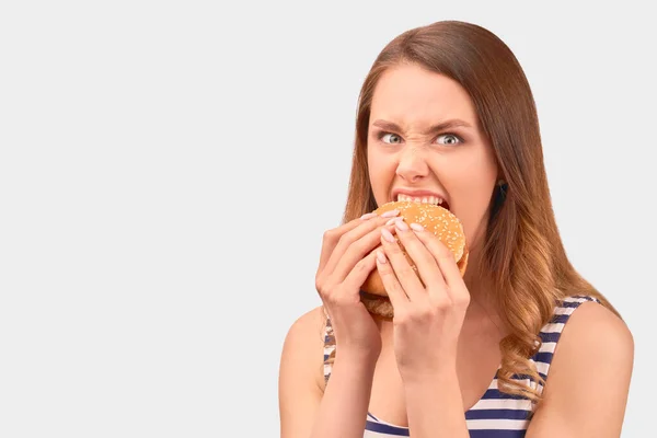 Cute girl quickly eats Burger, wrinkling nose — Stockfoto