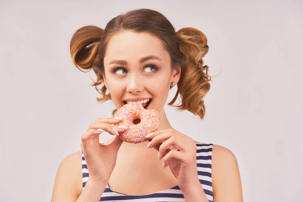 Happy girl holds donut and chews mouth full — Stockfoto