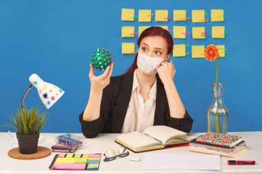 Maske takan kadın, topu koronavirüs şeklinde tutuyor.