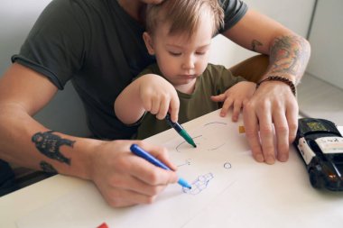 Genç baba iki yaşında oğluna yardım ediyor.