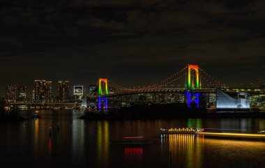 Aydınlatılmış Gökkuşağı Köprüsü 'nün bir resmi, gece (Tokyo).