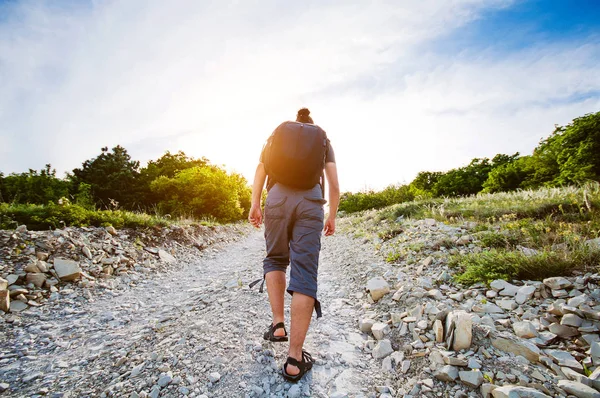 Hombre viajero levantándose por un camino rocoso — Foto de Stock