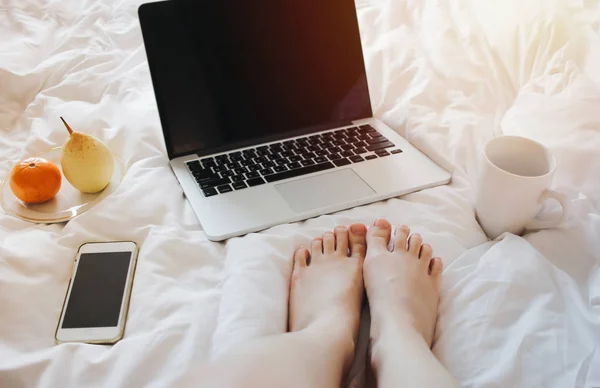 Woman using laptop on cozy bed — Stock Photo, Image