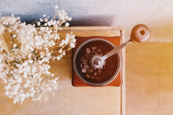 Кофемолка с цветами на столе — стоковое фото