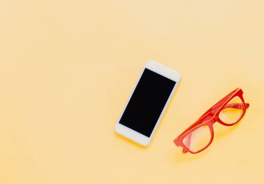 Parlak sarı arka planda akıllı telefon ve kırmızı gözlüklü yaşam tarzı ürünleri, moda tarzı yaz 
