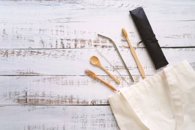 Çevre dostu yaşam tarzı konsepti, beyaz çantanın üst görünümü, tahtadan arka planda seyahat edilebilir ürün kiti. 