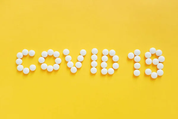 黄色の背景に単語Covid 19として薬の丸薬の形のフラットレイアウト ヘルスケアの概念とパンデミックCovid 19とコロナウイルスの普及を防ぐ — ストック写真