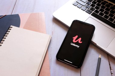 BANGKOK, Tayland - 2 Nisan 2020: Udemy uygulamasını ve dizüstünü bilgisayarla gösteren iPhone 'u kapat. Udemy, COVID-19 ve Coronavirus 'ta karantina sırasında popüler ve kullanışlıdır.