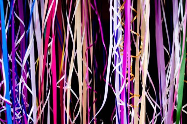 Siyah arka plan üzerinde renkli kurdeleler kıvrılmış