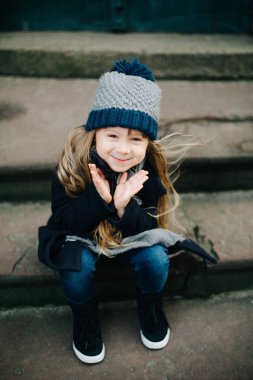 Küçük sevimli kız merdivenlerde oturan