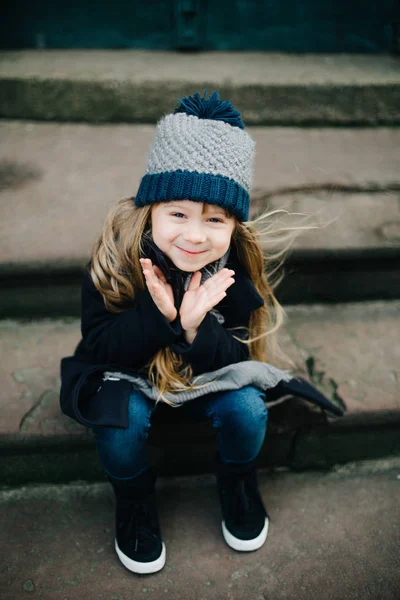 Kleines süßes Mädchen sitzt auf der Treppe — Stockfoto