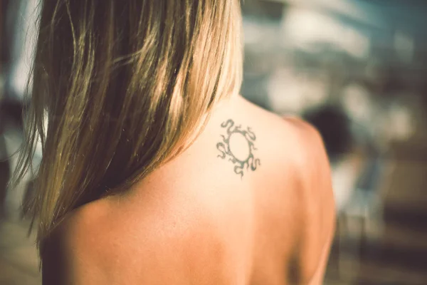 Tanned woman with tattoo on her back — Stock Photo, Image
