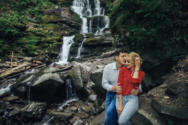 Milující dvojice poblíž vodopádu v lese. — Stock fotografie