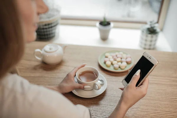 Vrouw met telefoon en hete thee — Stockfoto